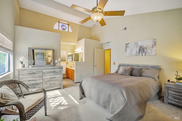 bedroom with light carpet, visible vents, a ceiling fan, ensuite bathroom, and high vaulted ceiling