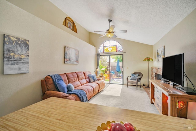 living room with a ceiling fan, a textured wall, carpet, vaulted ceiling, and a textured ceiling