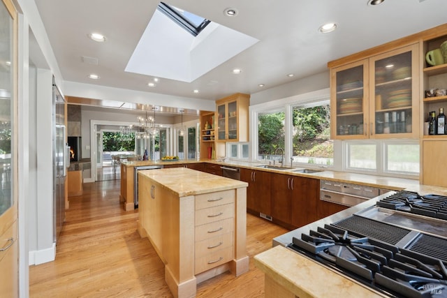 kitchen featuring hanging light fixtures, glass insert cabinets, light wood-style floors, a kitchen island, and a peninsula