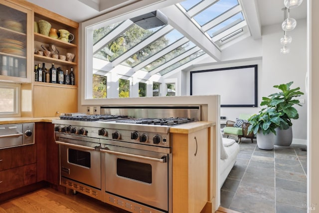 kitchen featuring a warming drawer, light countertops, lofted ceiling with skylight, and double oven range