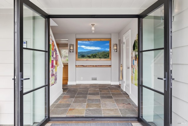 entrance foyer featuring baseboards, visible vents, stone finish floor, and french doors