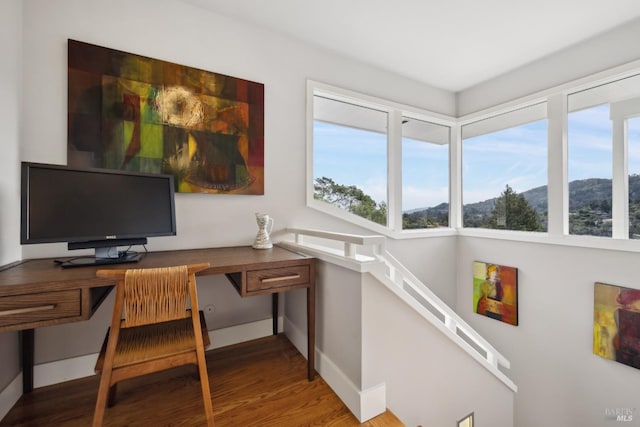 office area featuring a wealth of natural light, wood finished floors, a mountain view, and baseboards