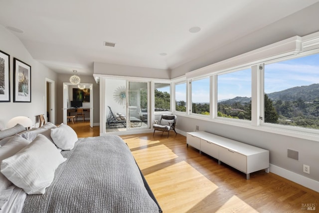 bedroom with light wood finished floors, visible vents, and baseboards