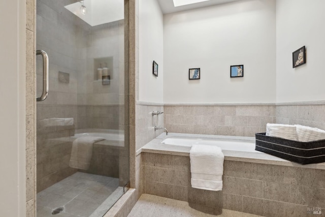 bathroom with a garden tub, wainscoting, a tile shower, and tile walls