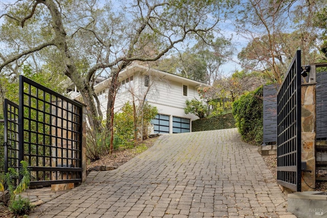 view of home's exterior with a garage, a gate, and decorative driveway