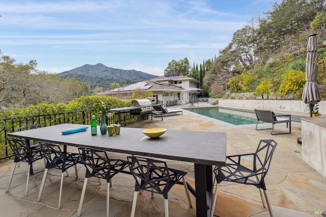 view of patio with a fenced in pool, outdoor dining area, a grill, and a mountain view