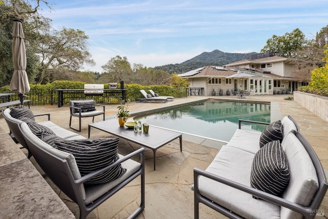 view of swimming pool featuring a fenced in pool, grilling area, a patio area, a mountain view, and an outdoor living space