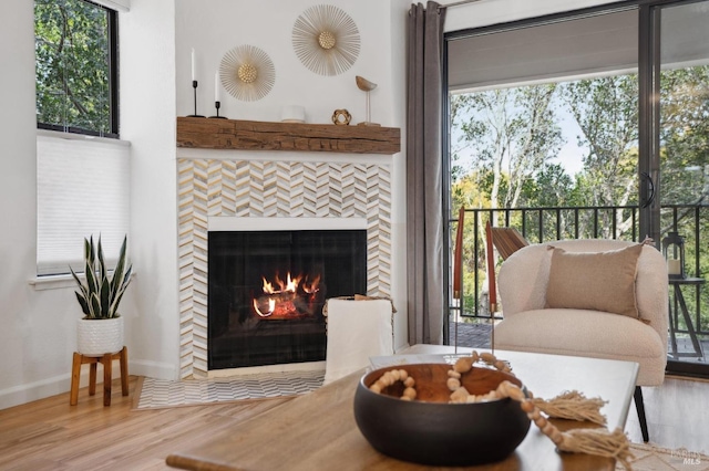 living area featuring baseboards, a tiled fireplace, and wood finished floors