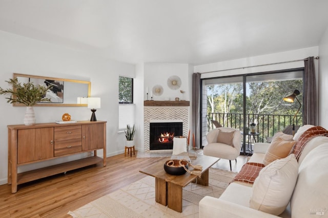 living room featuring baseboards, a fireplace, and light wood finished floors