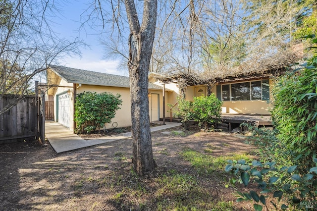 back of property with an attached garage, fence, and stucco siding