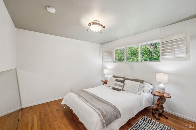 bedroom with baseboards and wood finished floors