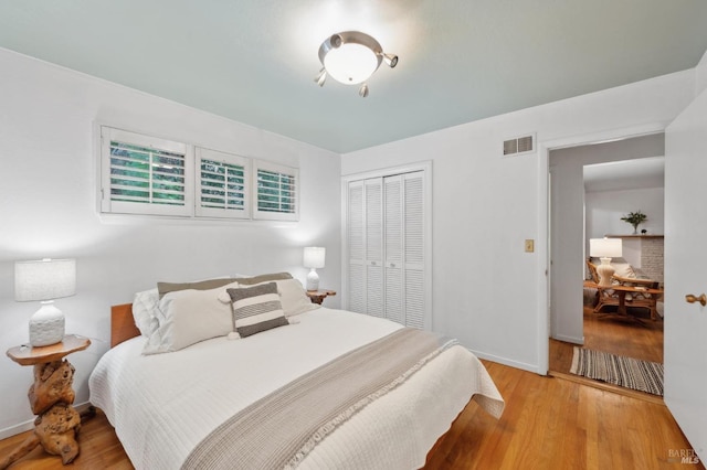 bedroom featuring a closet, visible vents, baseboards, and wood finished floors