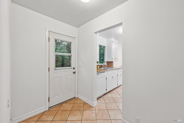 doorway to outside featuring baseboards, a sink, and light tile patterned flooring