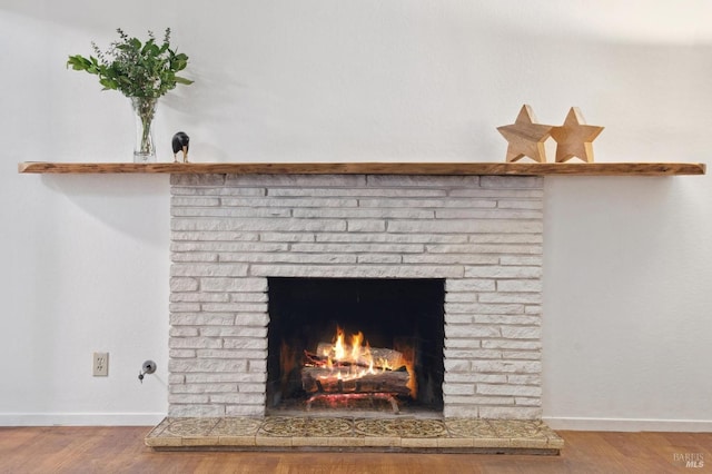 interior details featuring a fireplace, baseboards, and wood finished floors