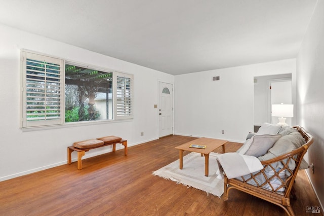 living area with visible vents, baseboards, and wood finished floors