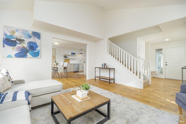 living room featuring light hardwood / wood-style flooring, sink, and high vaulted ceiling