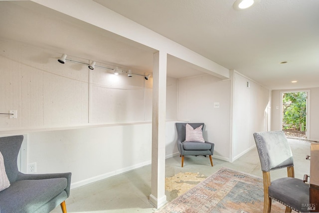 living area with concrete flooring and rail lighting