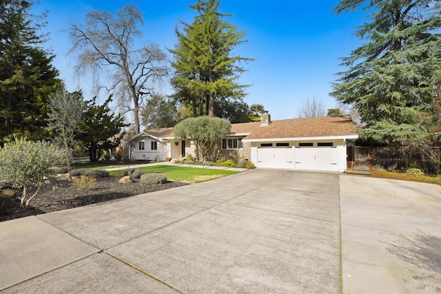 ranch-style home with fence, a front yard, a chimney, a garage, and driveway