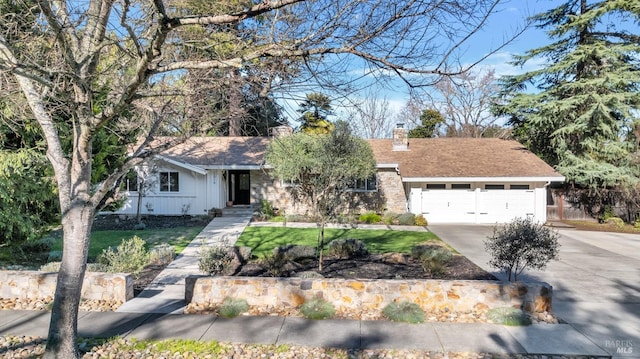 ranch-style house featuring a front lawn, roof with shingles, concrete driveway, an attached garage, and a chimney