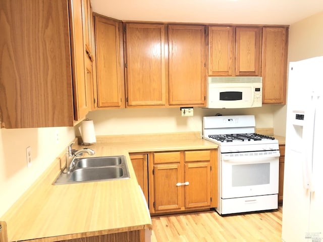 kitchen featuring white appliances, light wood-type flooring, and sink