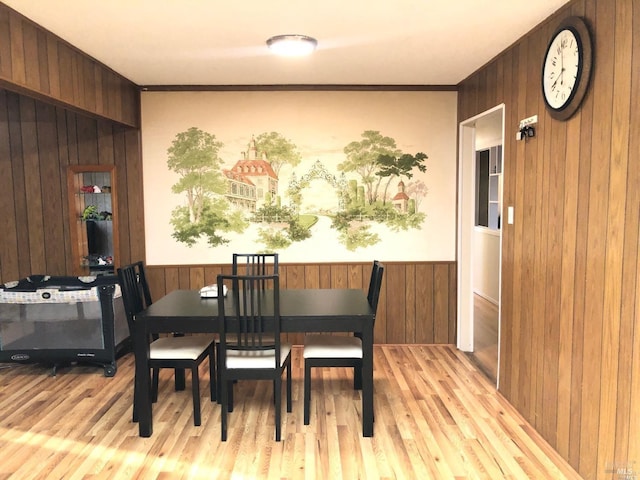 dining room featuring light wood-type flooring and wooden walls