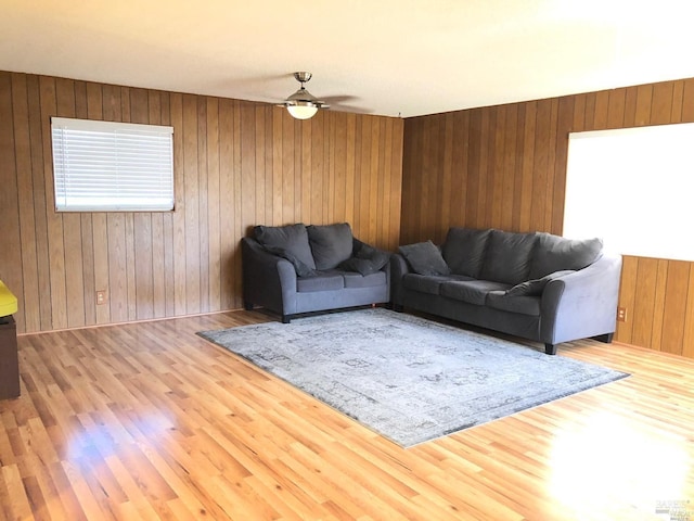 living room with wood walls, ceiling fan, and wood-type flooring