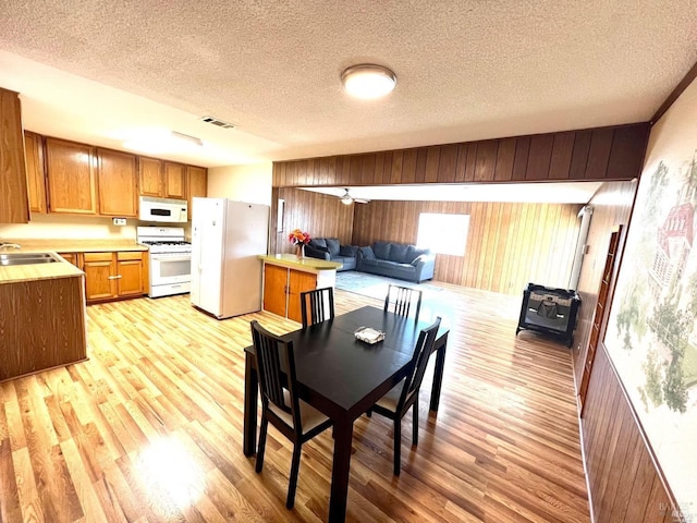 kitchen with sink, white appliances, a textured ceiling, and light hardwood / wood-style floors