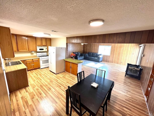 kitchen featuring sink, white appliances, light hardwood / wood-style flooring, and a kitchen island