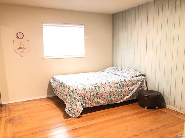 bedroom featuring hardwood / wood-style flooring and wood walls