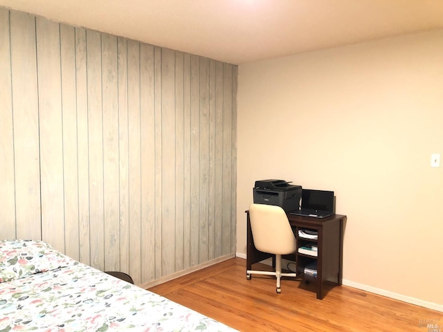 bedroom featuring light wood-type flooring and wooden walls