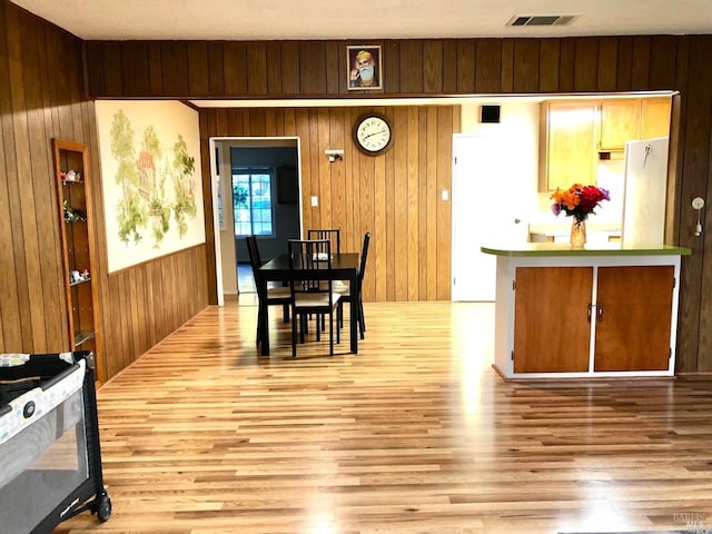 dining space with wooden walls and light hardwood / wood-style flooring