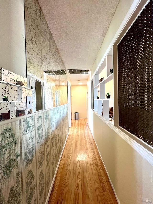 hallway featuring light hardwood / wood-style flooring and a textured ceiling