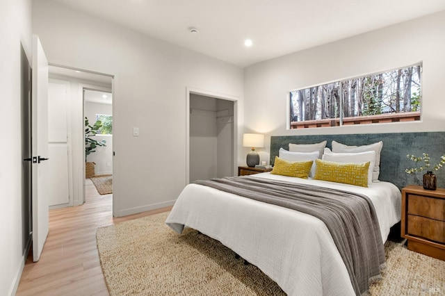 bedroom featuring light wood-type flooring, a closet, baseboards, and recessed lighting