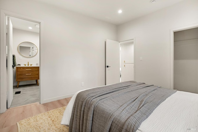 bedroom with connected bathroom, recessed lighting, baseboards, light wood-style floors, and a closet