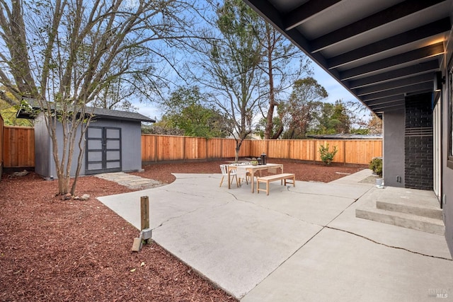 view of patio / terrace with outdoor dining space, a fenced backyard, an outdoor structure, and a shed