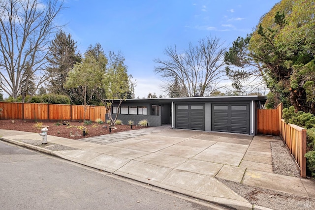 view of front of home with driveway, an attached garage, and fence