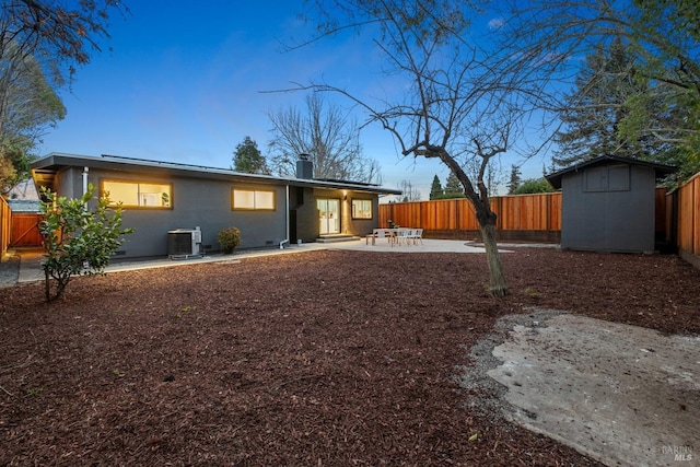 rear view of property with a fenced backyard, a storage unit, an outdoor structure, and a patio