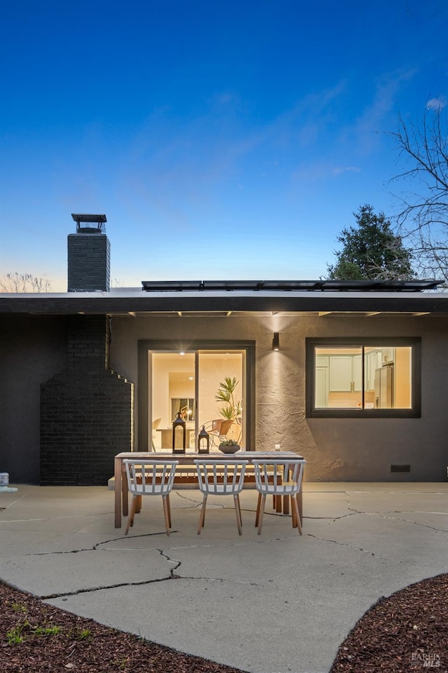 rear view of house with crawl space, a patio, a chimney, and stucco siding