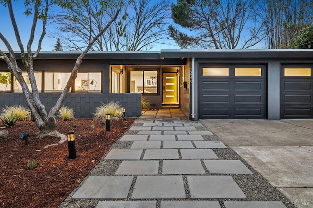 entrance to property featuring driveway, an attached garage, and stucco siding