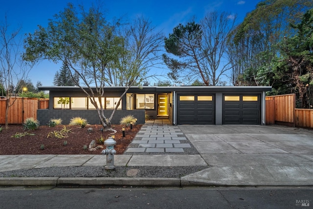 mid-century home with an attached garage, fence, and concrete driveway