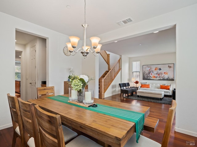 dining area with visible vents, baseboards, wood finished floors, stairway, and a notable chandelier