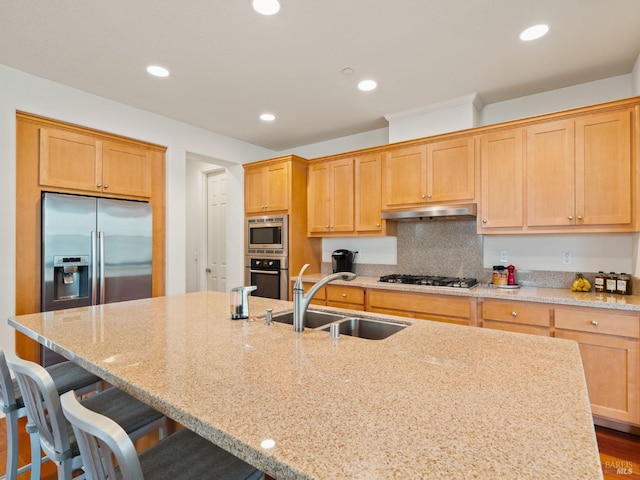 kitchen featuring appliances with stainless steel finishes, an island with sink, light stone countertops, and under cabinet range hood