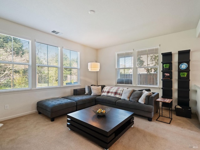 living area featuring visible vents, light carpet, and baseboards