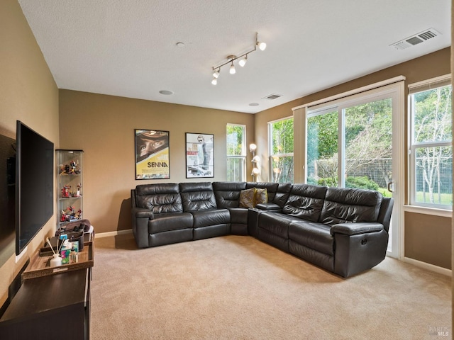 living room featuring carpet flooring, a textured ceiling, baseboards, and visible vents
