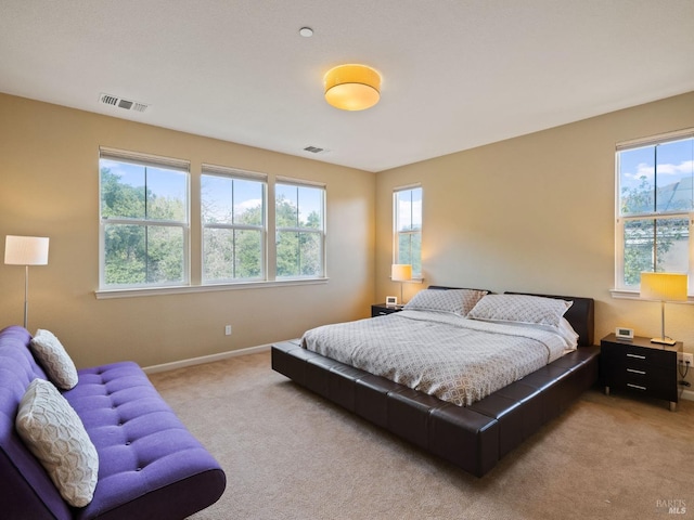 bedroom with multiple windows, light colored carpet, and visible vents