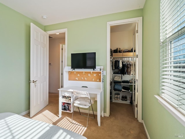 bedroom featuring baseboards, a walk in closet, a closet, and light colored carpet