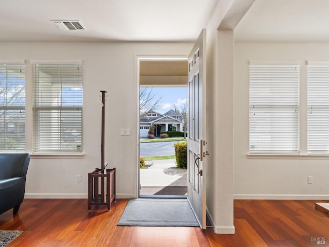 foyer entrance featuring baseboards, visible vents, and wood finished floors