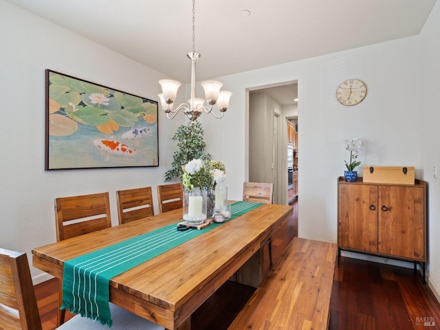 dining area with dark wood-type flooring and a notable chandelier