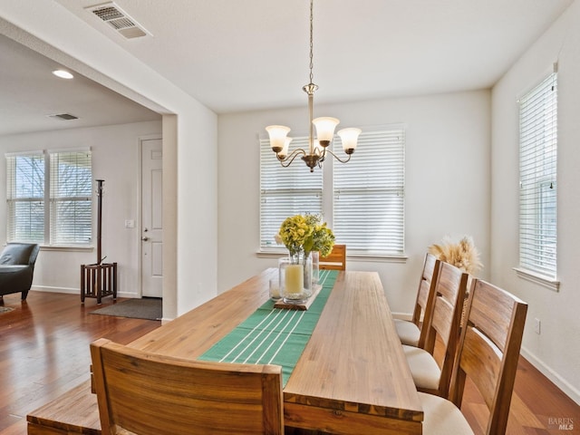dining room with baseboards, visible vents, a chandelier, and wood finished floors