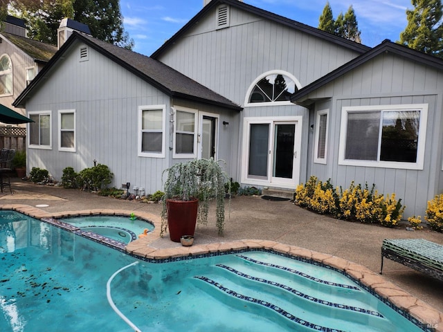 rear view of house with a patio and a swimming pool with hot tub